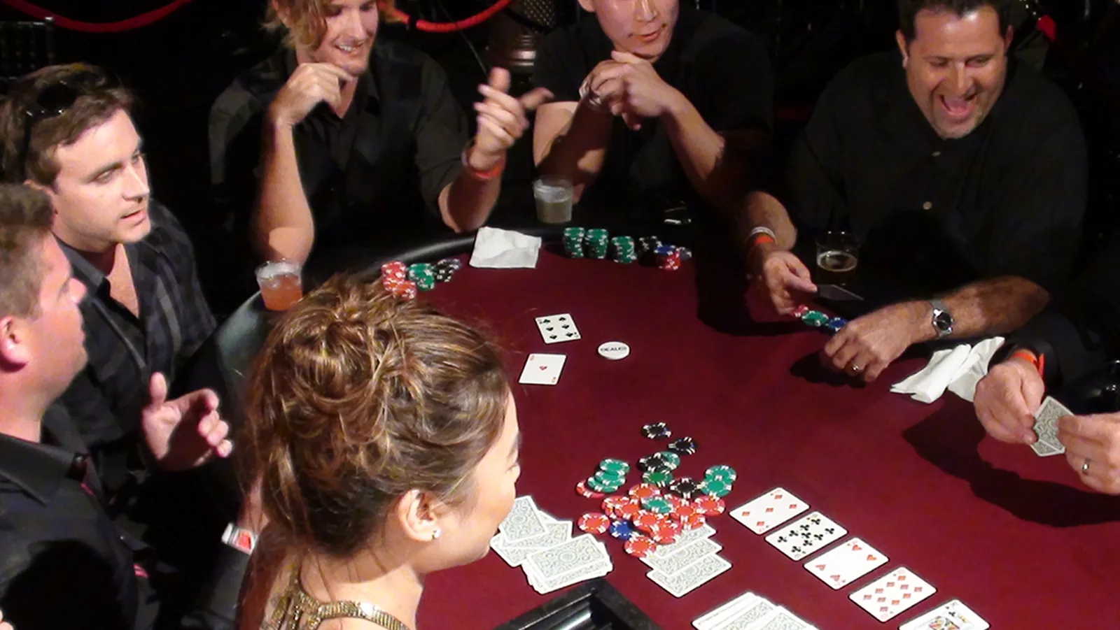 Guests playing a lively poker game at a casino party table with chips and cards